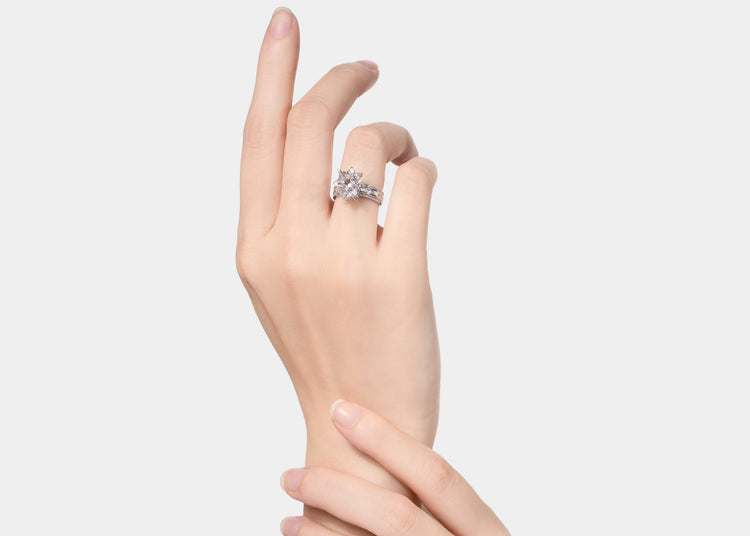 Hand wearing a diamond ring on a light gray background